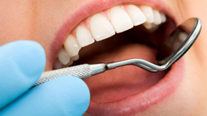 close up of a dentist using a mirror in patients mouth