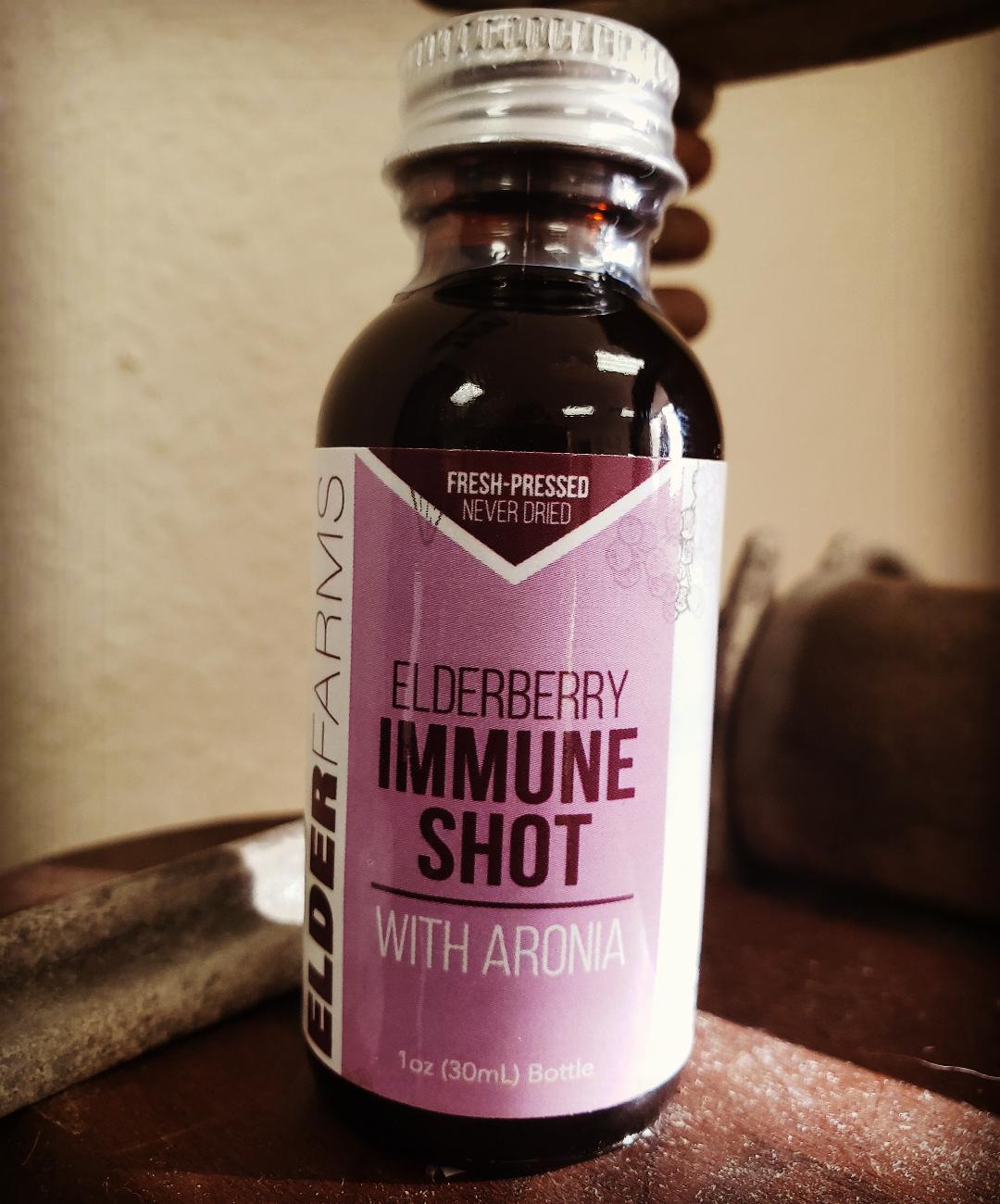 A bottle of Elder Farms Immunity Shot with Aronia, labeled as 'fresh pressed never frozen' and indicating 1 oz (29.5 ml) as the quantity.
