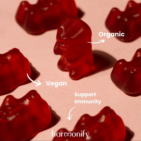 Red gummy bears on a pink background with 'Organic', 'Vegan', and 'Support Immunity' text, and 'harmonify' branding.