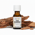Aura Cacia Texas Cedarwood essential oil with cedarwood bark behind bottle