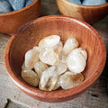 Pile of polished citrine stones in a wooden bowl on a rustic table
