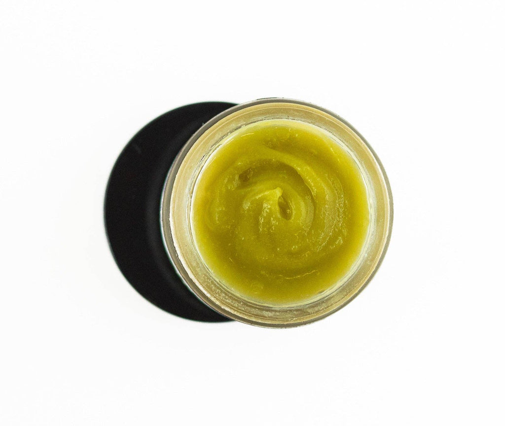 Jar of green cream with a black lid on a white background