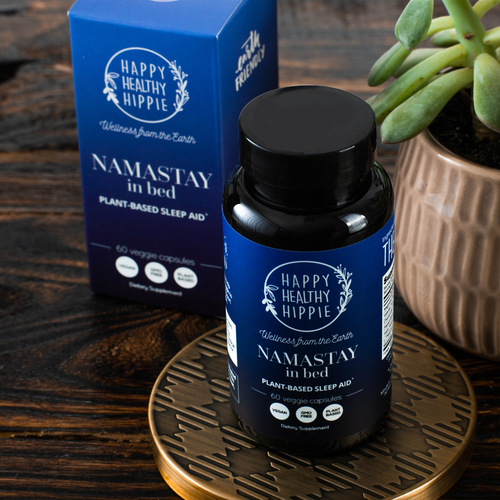 Happy Healthy Hippie Namastay in bed plant-based sleep aid bottle and packaging on a wooden surface with a plant.