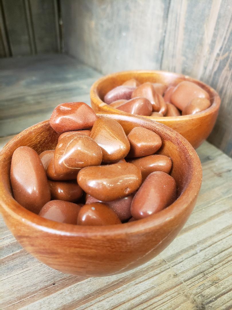 Wooden bowls filled with red jasper stones on a rustic background