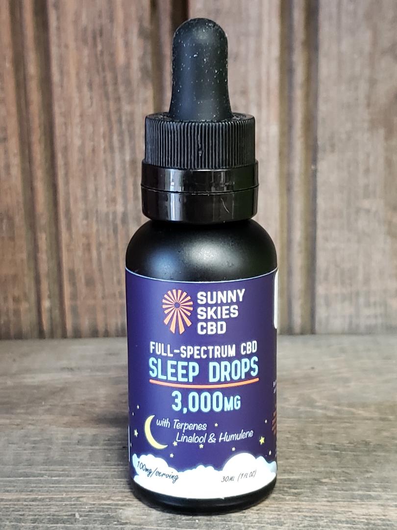Sunny Skies Full Spectrum Sleep Drops on a wood surface