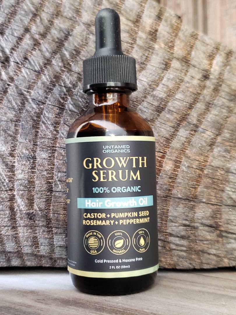 A bottle of Untamed Organics Hair Growth Oil with the label detailing the organic ingredients including Castor, Pumpkin Seed, Rosemary, and Peppermint.