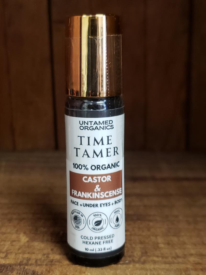 A roller bottle of Untamed Organics Time Tamer, which is a cold pressed castor oil and frankincense skin care product.